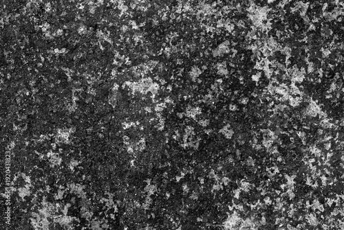 Dark rough textured background resembling coarse asphalt or hardened concrete, featuring uneven granular surface, dense shadows, and rugged industrial appearance.
