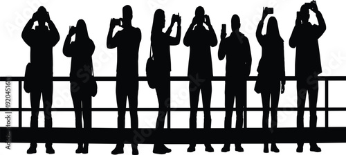 Black silhouette of a group of diverse tourists and people standing at a railing holding up smartphones to capture photos and video at sunse