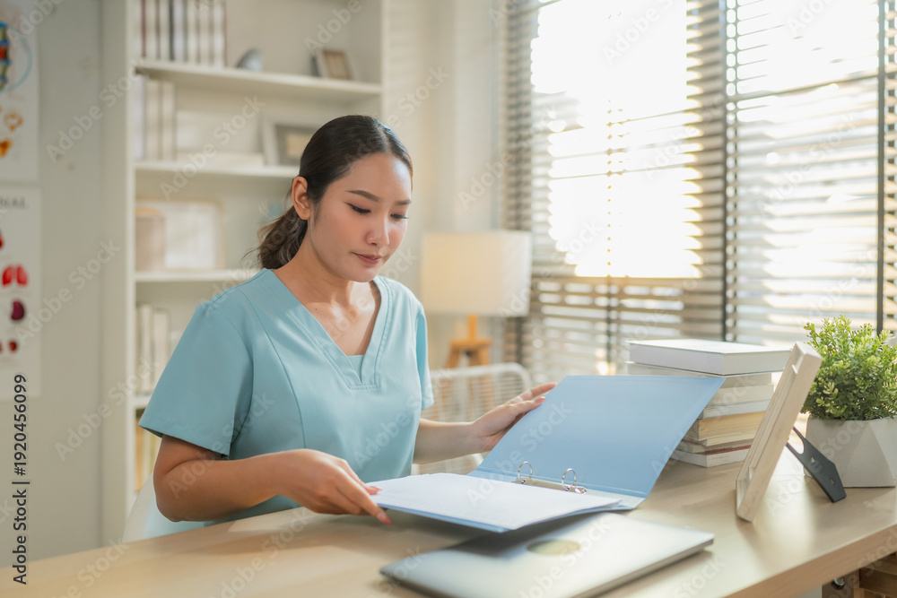 Obraz premium Female healthcare professional reviewing medical documents at desk with laptop in clinic office, administrative medical workflow, patient record management and modern healthcare documentation concept.