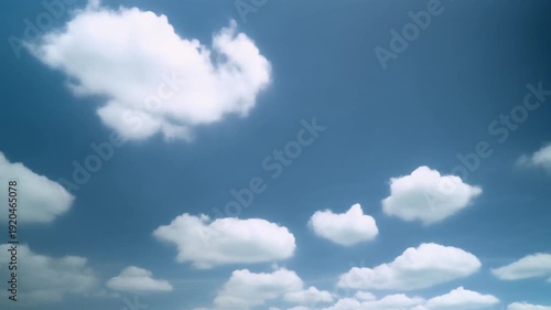 Fluffy white clouds drift across a clear blue sky, creating a beautiful natural scene