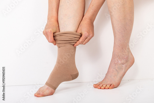 Obraz na płótnie Woman putting on compression knee-highs