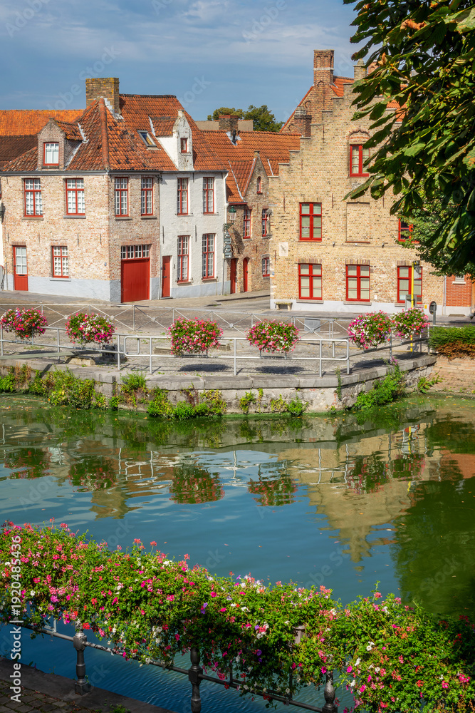 Fototapeta premium Medieval flemish architecture, houses reflecting in a canal, Bruges colorful cityscape with flowers in summer, Belgium