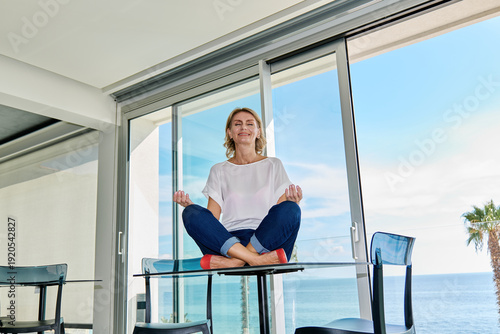 Smiling businesswoman sitting at lotus pose up the desk.