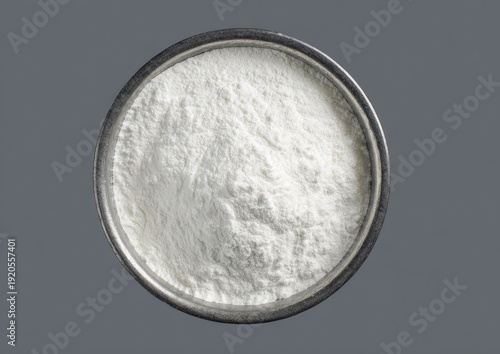 Overhead shot of a metal bowl filled with a white, powdery substance against a gray background