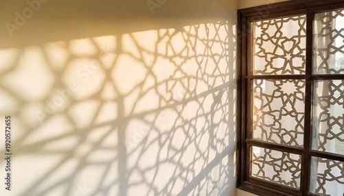Arabic geometric pattern shadow cast on wall from wooden window frame during sunny day creating ornamental light effects