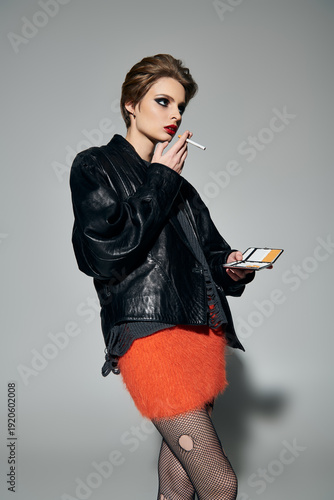 Konstfotografi Young beautiful woman in stylish outfit with a cigarette in a creative setting