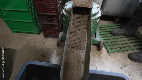 Wallpaper Mural Metal sieve positioned above a container, showing the process of filtering granules in a workshop setting with visible equipment and tools Torontodigital.ca