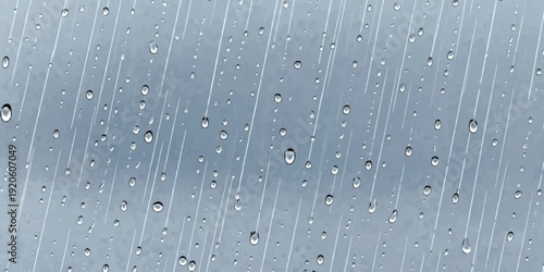 Close-up view of raindrops and streaks on a window pane during a grey, overcast day