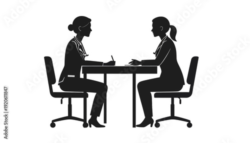 Two women sitting at a table facing each other in a meeting or interview setting.