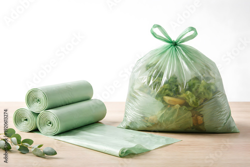 Green biodegradable trash bags with organic waste on wooden surface