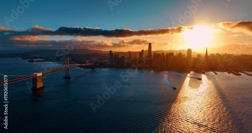 Two motor boats distancing from the waterfront of San Francisco, California, USA. City skyline is dazzled by the setting sun. Aerial view.