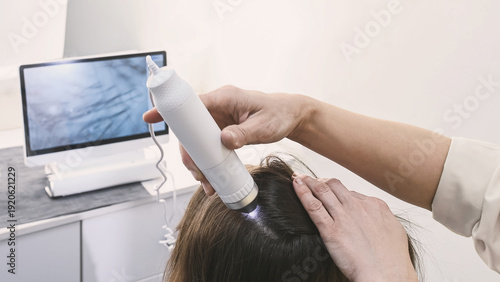 Photos Trichologist examines hair and scalp of young woman in salon using trichoscope and dermatoscope