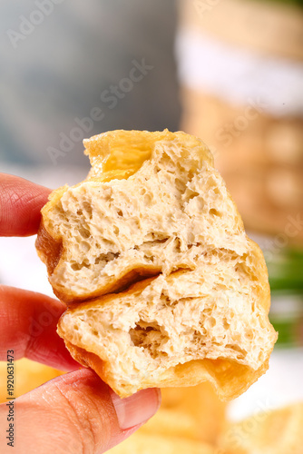 Deep-Fried Tofu Puff Hand Held Close-Up Showing Airy Texture of Golden Crispy Asian Bean Curd Cooking