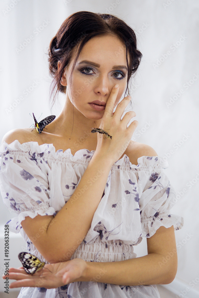 Fototapeta premium Young woman with butterfly and praying mantis on her hand and shoulder. Spring nature concept, connection with insects.