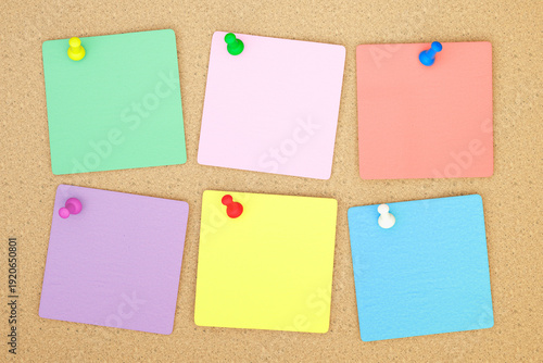 Colorful assortment of pinned sticky notes on cork board background. Organizational aids for reminders and tasks, perfect for office or educational use. Simple and effective method for notes