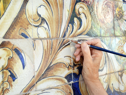 Obraz w ramie Reintegración cromática de azulejos de un panel cerámico. Trabajos de restauración y conservación de azulejos. Protección del patrimonio cultural de la ciudad. Restauradora de bellas artes trabajando