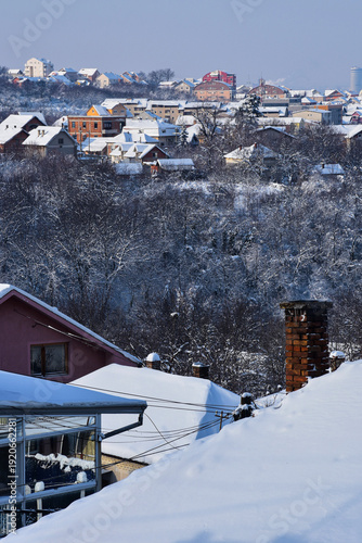 Winter landscape with snow-covered rooftops and misty hills in the distance
