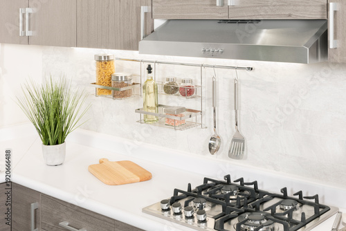 a kitchen counter with stainless steel cooking utensils and multiple metal cooking pans hanging from a wall mounted rack