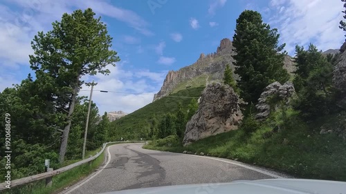 Summer Day In The Italian Dolomite, Canazei's Majestic Mountain Under Blue Sky in Italy, view from a moving car on the Road