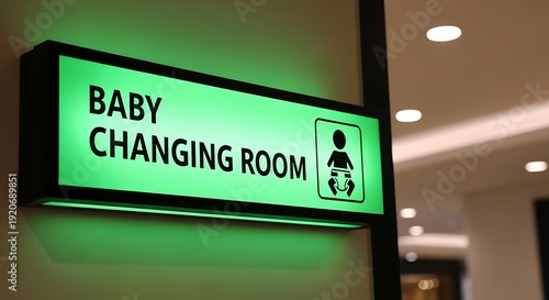 Illuminated green baby changing room sign with icon in building hallway baby changing room, sign, icon, green