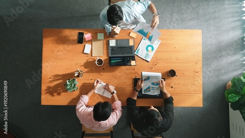 Top aerial view of caucasian business people sharing idea and writing report. Professional diverse people working together and brainstorming marketing plan at meeting table with graph. Convocation.