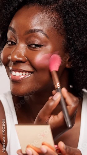 African American woman applying makeup.