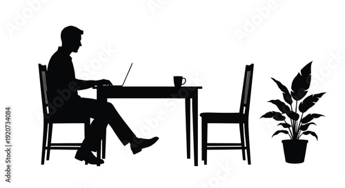 Silhouette of a businessman working on a laptop at a table alone.