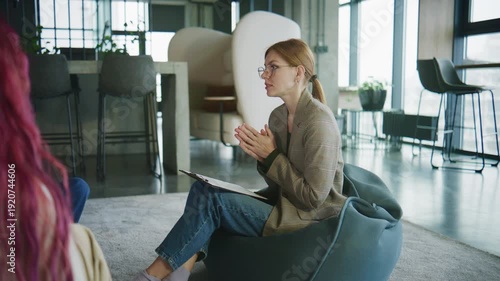 Women engage in discussion during psychology session aimed at personal growth and support in contemporary office setting