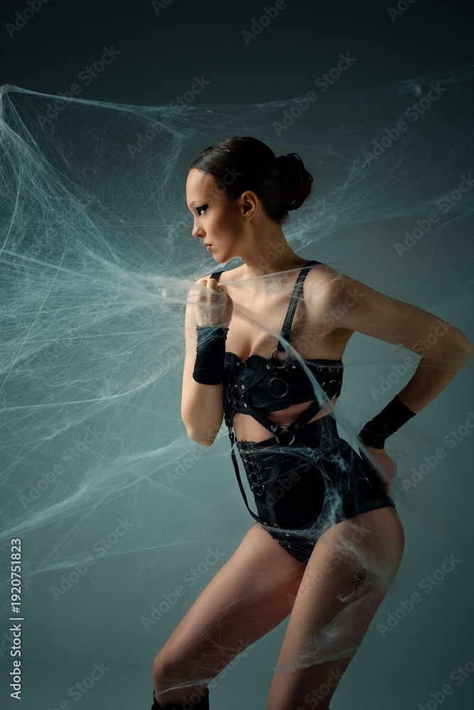 Obraz premium Gothic fashion concept of a woman in black lingerie trapped in spiderwebs.