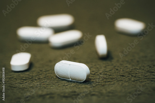 Cuadro en lienzo White oblong pills scattered on soft green background, pharmaceutical tablets on