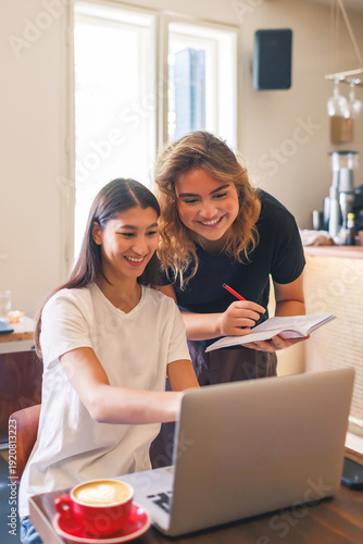 Two freelancers enjoying a productive moment while working on laptops in a cozy cafe together