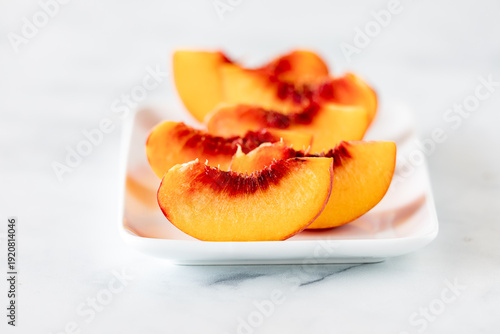 Cuadro en lienzo Slices of fresh freestone peaches on a white platter.