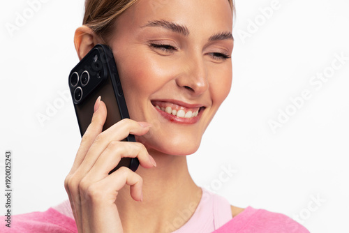 Smiling woman with clear skin holding smartphone near ear in studio on white background. Concept of communication, happiness, technology, connection, and positive mood in everyday life.