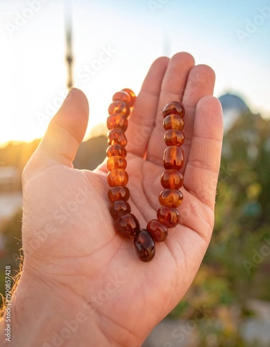 Wallpaper Mural Amber prayer beads held in a sunlit palm with mosque dome in background at sunset warm glow soft focus golden hour light Torontodigital.ca