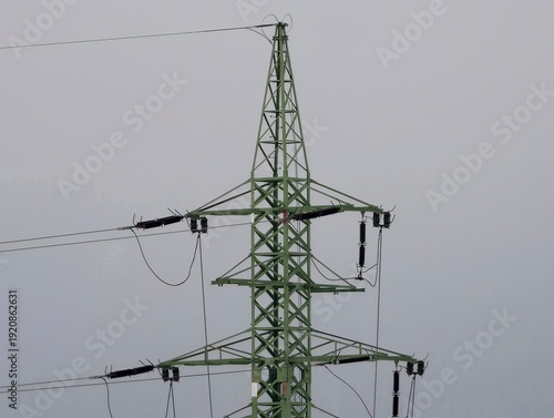 Detailed view of electrical towers with ceramic insulators under dark overcast weather conditions