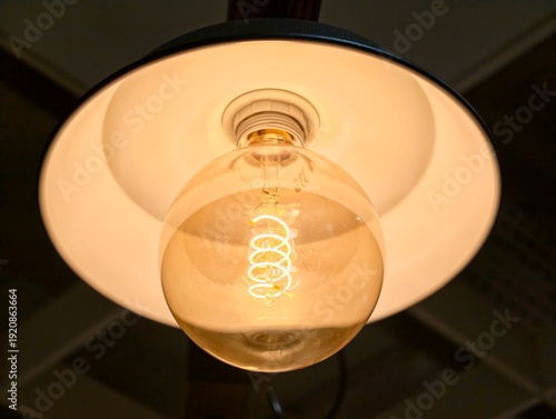 Cozy vintage lighting. Pendant lamp emits soft amber light illuminating textured ceiling and table