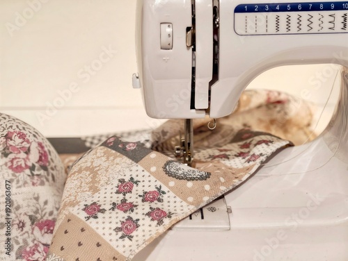 Focused shot of quilt stitching process. Intimate view of domestic machine sewing craftsmanship scene