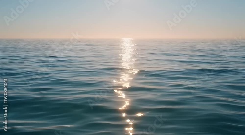 Calm ocean reflecting the sunlight at sunset creating shimmering water ripples