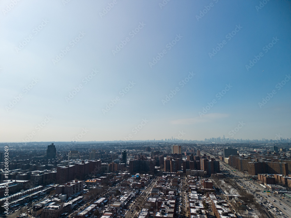 Obraz premium Aerial view showing forest hills, queens, with residential buildings and traffic on the long island expressway, extending towards the distant manhattan cityscape under a clear blue sky