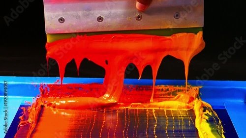 An artisan applies layers of warm colored inks on a screen, blending fiery hues to produce a smooth gradient. The image showcases the creativity and tactile approach of traditional hand printing