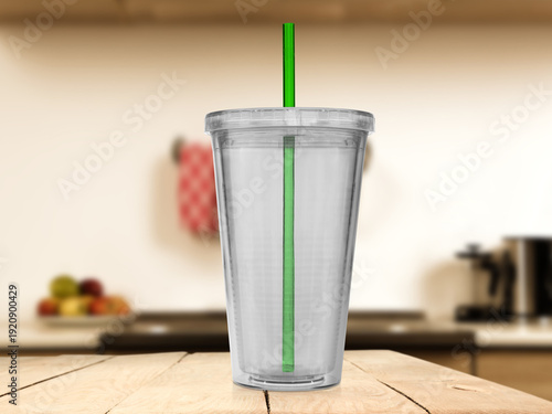 Transparent plastic cup with green straw placed on wooden table, kitchen background blurred. Reusable drinkware mockup suitable for branding, lifestyle advertising, beverage presentation, and product 