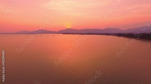 Above the mountain range, a sweet and serene sunset sky unfolds clouds tinged with rose and lavender hues, glowing softly as daylight gives way to the tender calm of evening.