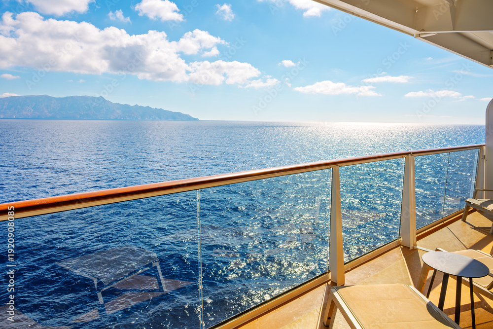 Fototapeta premium A large private stateroom suite balcony aboard a large cruise liner as it passes by islands in the Mediterranean Sea.
