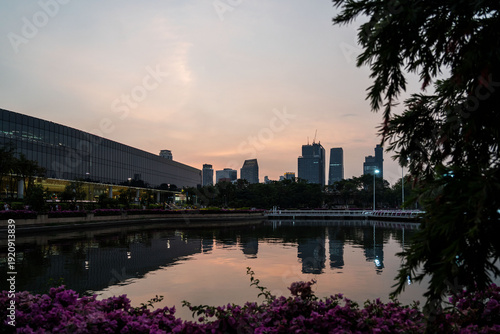 Modern architecture of Queen Sirikit National Convention Center reflected in lake of Benjakitti Park at sunset in Bangkok