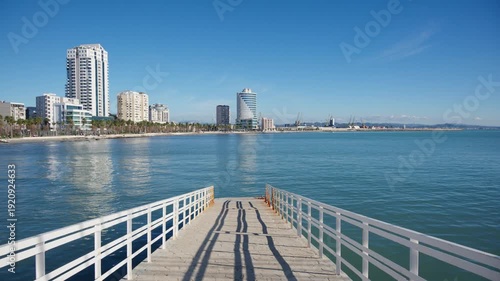 Wallpaper Mural Concrete pier extending into the tranquil Adriatic Sea towards the Durres waterfront cityscape Torontodigital.ca