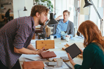 Team of designers reviewing material samples in creative studio