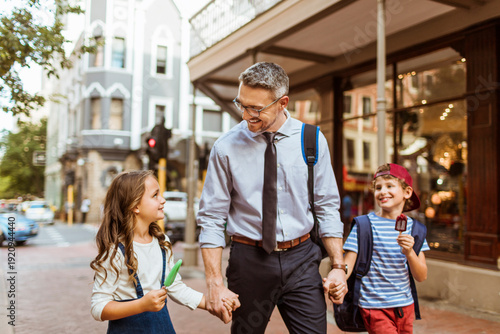 Father walking with children on city street after school