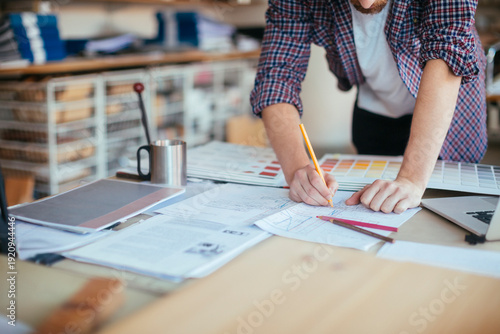 Photos Designer drafting plans with color swatches in studio