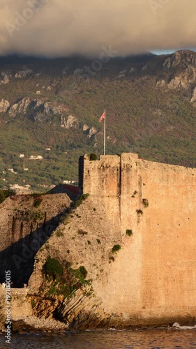 Budva Old Town citadel walls and church tower overlooking the Adriatic Sea, with mountains in background