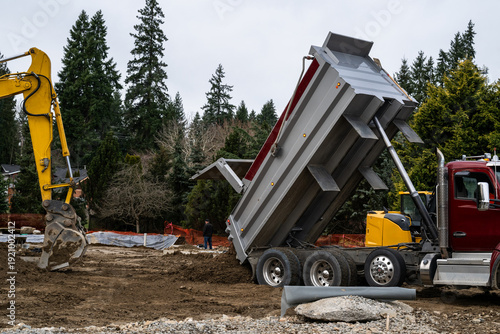 Fotografie Dump truck delivering clean dirt, mineral soil, to a construction job site, hydr